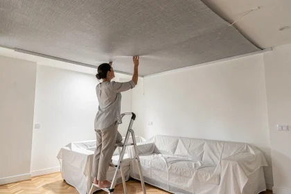 Femme installant un plafond toile tendue dans un salon moderne lors d'une rénovation sans gros travaux